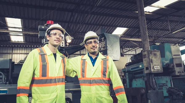 Group of factory workers using machine equipment in factory workshop