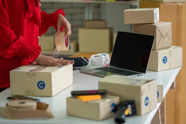 Çevrimiçi satıcı ev ofisinde çalışıyor ve teslimat kutusunu müşteriye paketliyor..