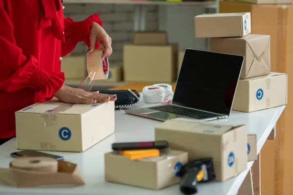 Онлайн-продавец работает в домашнем офисе и упаковывает доставку коробки клиенту. — стоковое фото
