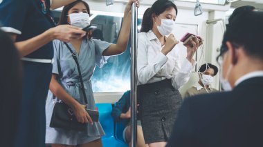 Kalabalık bir metroda maske takan insanlar.