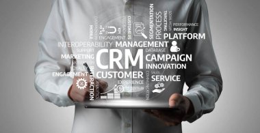 A business professional uses a digital tablet to analyze customer relationship management data, highlighting marketing strategies and innovative service approaches in a modern workspace. Tessel