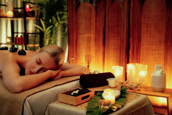 Lüks tatil köyündeki kaplıcalarda sıcak taş masajı, sıcak mum ışığı, spa bazalt taşı masajının keyfini çıkaran mutlu kadın müşteriler, rahatlatıcı bir sıcaklıkla vücudun üzerinde süzülüyorlar. Sessiz.