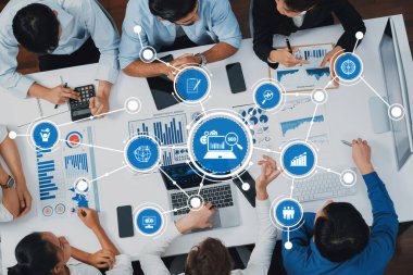 A group of professionals collaboratively engaging in a business strategy session, analyzing data and insights using technology and visual graphs for informed decision-making. Amity