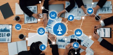 A vibrant and engaging business meeting scene showcasing hands actively collaborating over graphs, charts, and digital devices on a wooden table. Amity