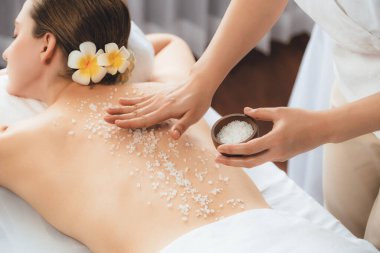Lüks spa salonlarında sıcak mum ışığında cilt bakımı yaptıran kadın müşteri. Sağlık Spa vücut fırçasında tuz temizleme güzellik tedavisi. Sessiz.