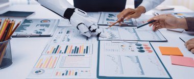 Fütüristik bir düzende, stratejik bir toplantı sırasında iş ekibine veri analizinde yardımcı olan bir robot kolu, profesyonel ortamlarda teknolojiyi ön plana çıkarıyor. Noogenesis