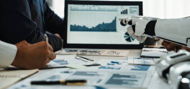 Bir iş ortamında insan ve robot takım çalışmasını gösteren dinamik bir sahne. Gelişmiş üretkenlik için analitik grafikler, veri görselleri ve modern teknoloji entegrasyonu. Noogenesis