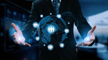 Profesyonel bir işadamı, küresel ticari işbirliği ve etkileşimin modern konseptini gösteren bağlantılar ve insan simgelerinin yer aldığı dijital bir dünya haritasına doğru hareket eder. Dörtgen