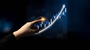 A hand touches a digital financial chart displaying a rising graph with candlestick indicators, symbolizing investment success and business growth insights. Impute