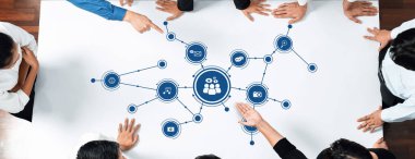 A group of individuals engaging collaboratively at a table, illustrating various media connections and interactive concepts, ideal for visualizing teamwork and communication. Amity