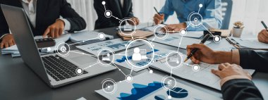 A diverse group of professionals collaborates in a modern office during a business meeting. They analyze data and discuss strategies through engaging visual presentations and teamwork. Amity