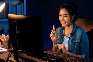 Sunucu kanalı Asyalı etkileyicisi canlı yayında konuşuyor. Sosyal medyada kulaklık takıyor, bilgisayar kaydı yapıyor, dinleyicileri selamlıyor ve Neon Modern Stüdyoları 'nda online olarak koçluk yapıyor. Taktik.