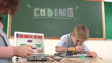 Kafkas akıllı çocuk kök teknoloji dersinde tornavida kullanarak ana tahtayı tamir ederken aynı zamanda gülümseyen öğrenci de dizüstü bilgisayar ekranı kodlu elektronik makineyi incelemek için birlikte çalışıyor. Pedagoji.