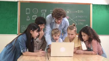 Kafkas öğretmeni ve çeşitli öğrenciler sınıfta dizüstü bilgisayara bakıyor. Kodlama programını öğrenen ya da öğretmenlik yaparken yazılım kullanarak oluşturulan çok kültürlü çocuklar. Pedagoji.