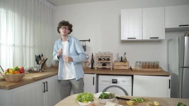 Mutlu baba yemek pişirirken müziğe geçiyor ve modern mutfakta öğle yemeği hazırlıyor. Aktif baba, sebze ve mutfak gereçleri ile çevrili sağlıklı yemek ya da salata yaparken şarkıyla dans ediyor. Pedagoji.