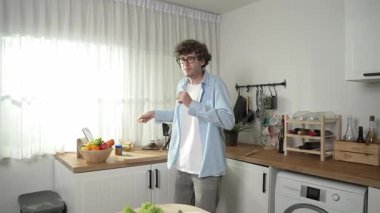 Mutlu baba yemek pişirirken müziğe geçiyor ve modern mutfakta öğle yemeği hazırlıyor. Aktif baba, sebze ve mutfak gereçleri ile çevrili sağlıklı yemek ya da salata yaparken şarkıyla dans ediyor. Pedagoji.