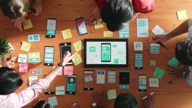 Ux ui tasarımını renkli yapışkan nota üzerine yazmak için birlikte çalışan geliştirici ekibinin üst görüşü. Tablet 'te kablo prototipi inceleyen ve yazılım tasarlayan bir grup programcı. Cemaat.