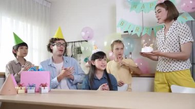 Asyalı kız dilek tutarken ve doğum günü mumu üflerken pasta yiyor. Kafkasyalı anne pasta tutuyor ve enerjik çocuk mum üflerken kızına yerleştiriyor. Güzel bir aile el çırpıyor. Pedagoji.