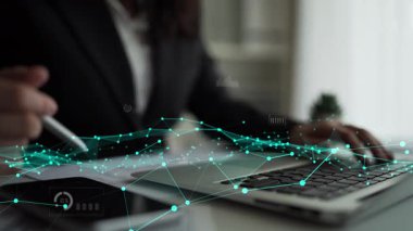 Bir iş adamı, çağdaş ofis ortamında modern analitik teknikler sergileyerek bir dizüstü bilgisayarda çeşitli dijital grafik ve çizelgelerle ilgilenir. Xenic