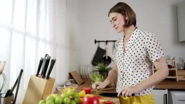 Kafkaseli anne kahvaltıda sebze pişirirken mutlu anne de modern mutfakta salata için taze malzemeler hazırlıyor. Hizmetçi sağlıklı yemek pişiriyor. Dikkat konsepti. Pedagoji.