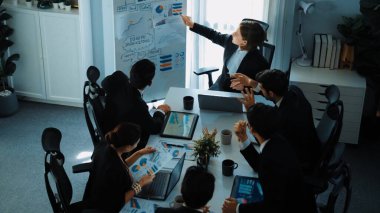 Akıllı yönetici projesinin üst görünümü beyaz tahtaya zihin haritası ve finansal grafik ile işaret ediyor ve çeşitli yatırımcılar hisse yatırım grafiğini dinleyip analiz ederken pazarlama fikrini açıklıyor. Müdürlük.