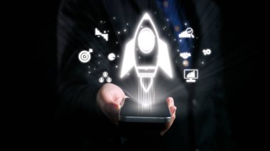 A hand holding a smartphone with a glowing rocket icon, symbolizing business launch and technology growth. Graphics evoke innovation and modern progress in digital realms. Qubit
