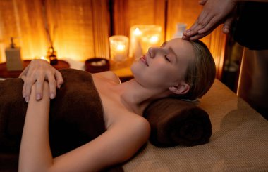 Beyaz kadın stres önleyici kafa masajı yapmaktan ve lüks otel veya otelde sıcak mum ışığında yüz güzelliği eğlencesi yapmaktan zevk alıyor. Sessiz.