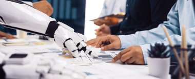 Bir robot ve insan takımı modern ofis ortamında stratejik karar verme mekanizması için veri ve grafikleri analiz ederek çalışmanın geleceğini gözler önüne seriyor.