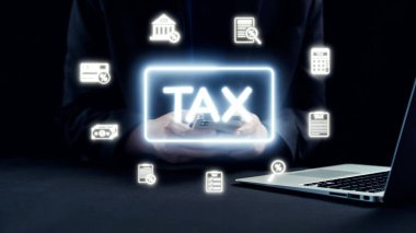 Dijital Vergi Sembolleri ile Modern Vergi İdaresi Konsepti ve Karanlık Bir Çevrede Akıllı Telefon ve Laptop Kullanan Kişiyi Çevreleyen Mali Simgeler. Dörtgen