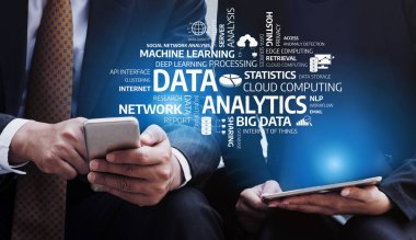 Günümüzde dijital ortamda veri analizi, bulut hesaplaması ve makine öğrenmesinin önemini gösteren iki iş adamı mobil cihazları modern bir ortamda kullanıyor. Tessel