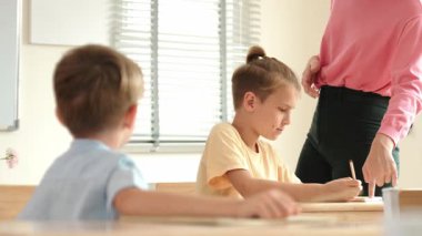 Beyaz bir çocuk ödevlerini yaparken ve açıklama dinlerken güzel bir öğretmen sınavı açıklıyor. Sınıfta not alırken ya da kağıda cevap yazarken öğretmenine bakan sevimli bir çocuk. Pedagoji.