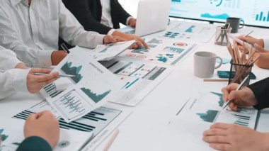 A diverse business team collaborates around a conference table, focusing on data charts and digital displays, fostering strategic planning and insightful discussions. SACTR