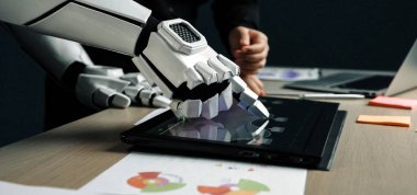 Robot bir el modern bir çalışma alanında dokunmatik ekranlı bir bilgisayarla temas kurar. İnsan varlığı veri analizi, sergilenen yenilikler konusunda işbirliği öneriyor.