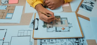 Bir tasarımcı ustalıkla, eskizler, ilham panoları ve temel tasarım araçlarıyla dolu canlı bir çalışma alanında mimari düzenler ve planlar oluşturur. SACTR