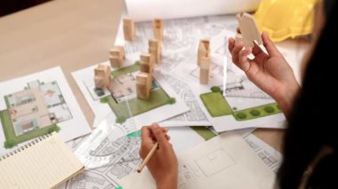 Mimar ve mühendis, mimari belge, ölçüm aracı ve ahşap bloğu ofis çevresinde dağıtan planlar kullanarak inşaat inşaatı hakkında düşünür veya tartışır. Tanımlama.