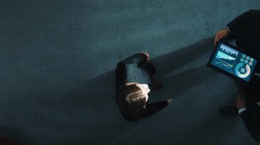 Zeki yöneticinin çeşitli takımlarla tokalaştığı ve tabletteki finansal verileri analiz ettiği yukarıdan aşağıya hava görüntüsü. Kadın lider bir anlaşma yaparak gruba katılıyor ve pazarlama stratejisini paylaşıyor. Müdürlük.