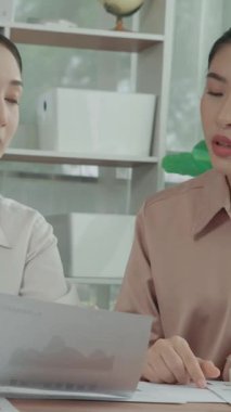 Ofis çalışma alanında birlikte çalışan iki genç hevesli iş kadını. Genç meslektaşlar tartışırken ve dizüstü bilgisayar kullanırken. Modern ofis çalışanları masada birlikte oturuyorlar..