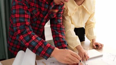 Mimarlık ve güvenlik mühendisi, modern ofiste doğruluk için mimari belge ve ölçüm aracı kullanılarak dizüstü bilgisayarın üzerinde sergilenen planlar hakkında tartıştı. - Yakın çekim. Tanımlama.
