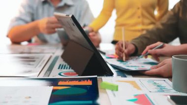 Engaging collaborative meeting in a bright office environment, featuring digital devices, colorful charts, and focused team members discussing strategies and data insights. SACTR