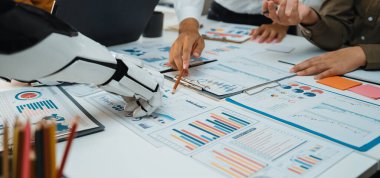 Bir insan ve robot arasındaki işbirliğini gösteren modern bir ofis sahnesi ayrıntılı rapor ve çizelgeleri analiz ederken, veri odaklı karar alma konusundaki yenilik ve takım çalışmasını vurguluyor. Noogenesis