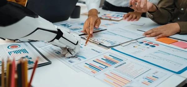 Bir insan ve robot arasındaki işbirliğini gösteren modern bir ofis sahnesi ayrıntılı rapor ve çizelgeleri analiz ederken, veri odaklı karar alma konusundaki yenilik ve takım çalışmasını vurguluyor. Noogenesis