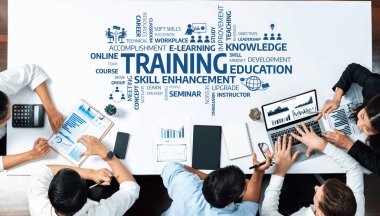 A diverse group of professionals collaborates in an e-learning training session, using laptops and data charts to enhance their skills and develop knowledge in a modern workspace. Amity