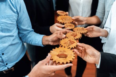 This stock photo captures hands holding wooden gears featuring financial symbols, emphasizing collaboration in business and tax planning for effective teamwork. Amity