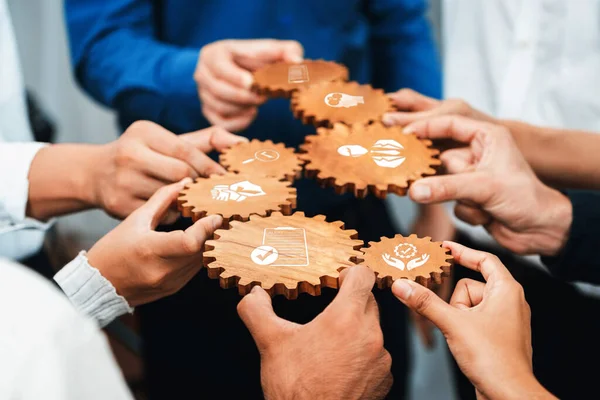 Hands join together to hold wooden gears, showcasing collaboration and teamwork in a business environment. Each gear represents ideas and concepts essential for success. Amity