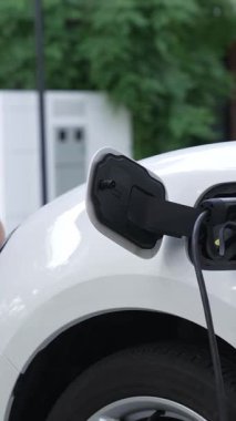 Bir kadın evinde elektrikli araç şarj aletinin fişini çekiyor. İlerici bir yaşam tarzında elektrikli araçların kullanımı, temiz ve sağlıklı bir çevreye katkıda bulunur..