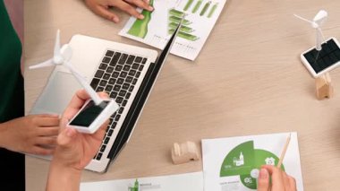 Eko evi projesini yel değirmeni tasarım modeli ve karbon ayak izini azaltmak için yeşil enerji kullanım grafiği ile toplantı masasında tartışan harika bir iş ekibi. Dünyayı kurtarın. Eline odaklan. Tanımlama.