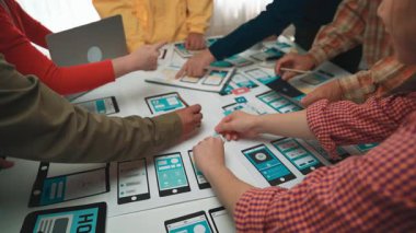 A diverse group of people collaboratively engaging in a digital project in a modern workspace, utilizing smartphones and tablets for brainstorming and creative development. SACTR