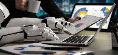 Bilgisayarda veri grafiklerini analiz eden, iş ortamlarında teknoloji ve verimliliğin kaynaşmasını gösteren modern bir ofis sahnesi. Noogenesis