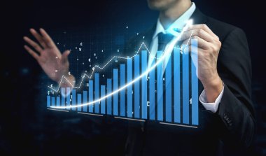 Bir işadamı, dijital ekranda grafik ve eğilimleri gösteren ve büyüme ve başarıyı vurgulayan finansal verileri sunarak, çağdaş bir ofiste güven içinde duruyor. Etki