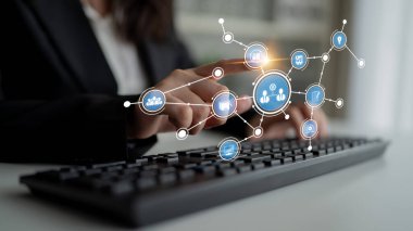 A business professional interacts with a keyboard while digital connection icons appear, symbolizing networking and technology in a modern office setting. Tessel